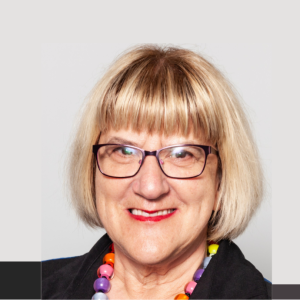 Headshot of a blond middle-aged woman with chin length hair and glasses.