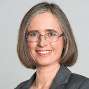 In Mojo's headshot, she has grey hair in a bob and is smiling at the camera and is wearing glasses. She has a plain grey background.